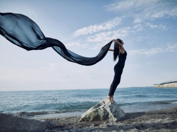 a woman standing on top of a rock near the ocean